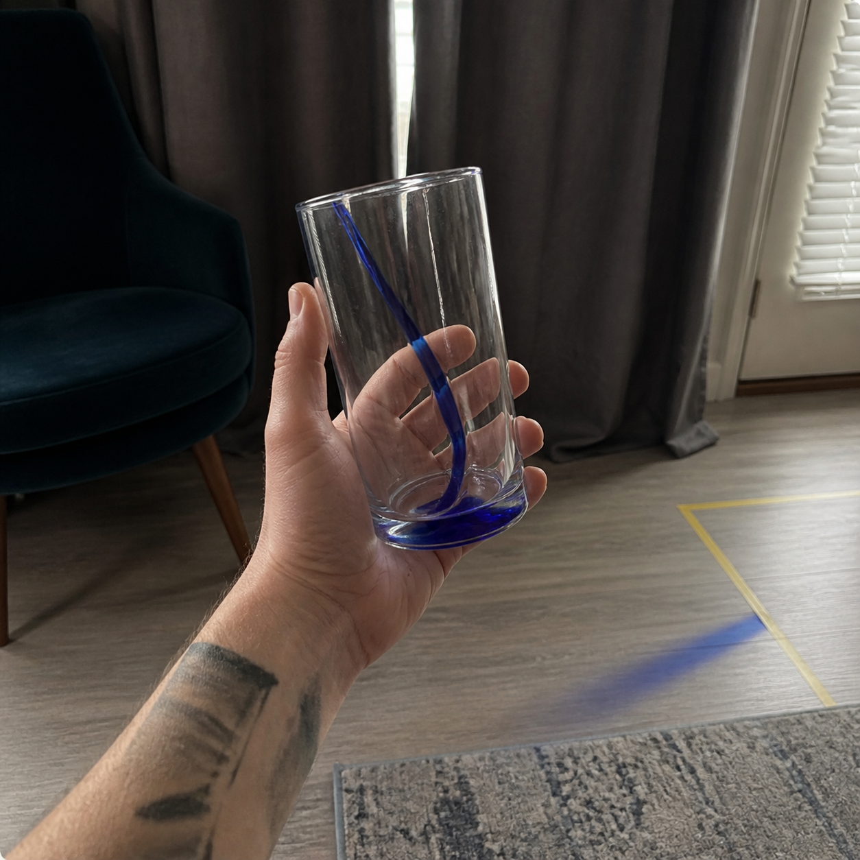 The original DRIP release image: a hand holding a glass with a blue line, and blue light across the floor.